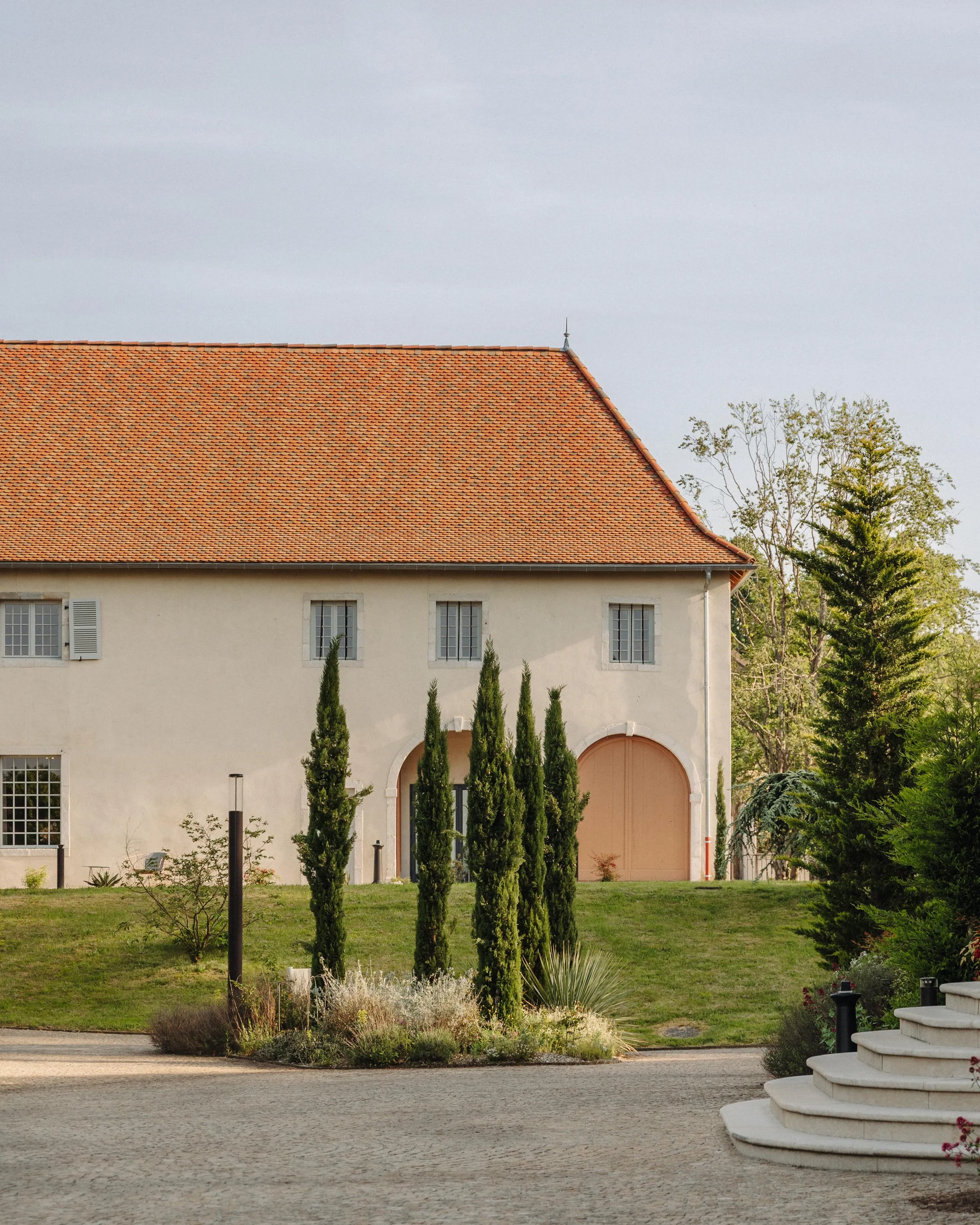 Building with red roof, trees, and a path in front